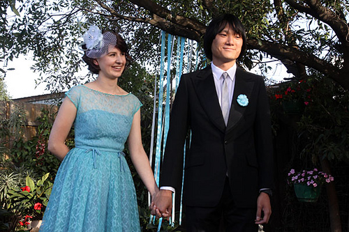 couple holding hands beneath ribbon tree