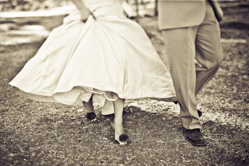 bride and groom walking through vineyard