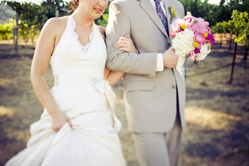 bride and groom walking through vineyard