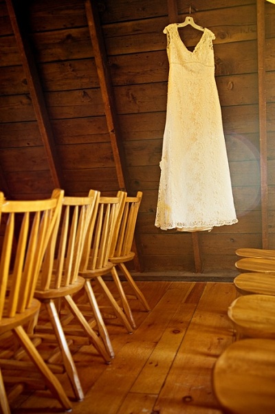 lace wedding dress hanging in barn