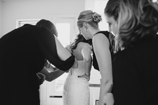 bridesmaids buttoning up bride's dress