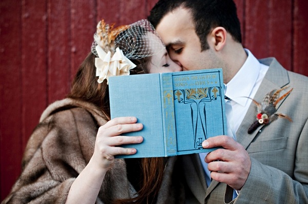 bride and groom kissing behind vintage book