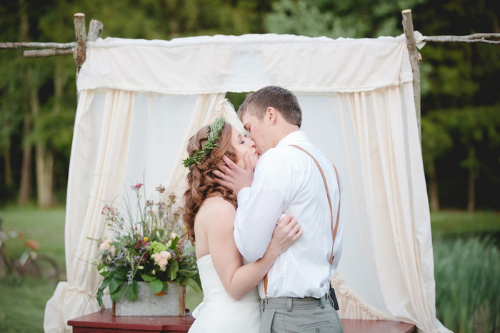 bride and groom first kiss on tree farm