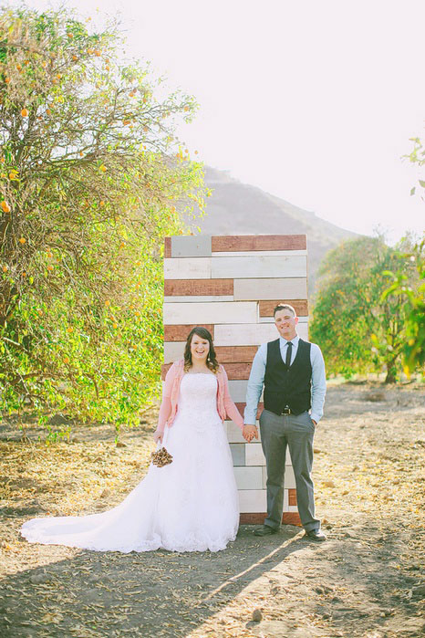 bride and groom in front of wooden ceremomy back drop