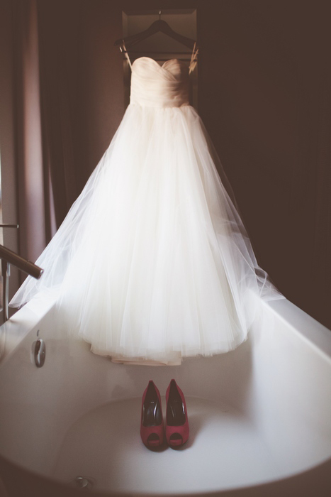 tulle wedding dress hanging in bathtub 