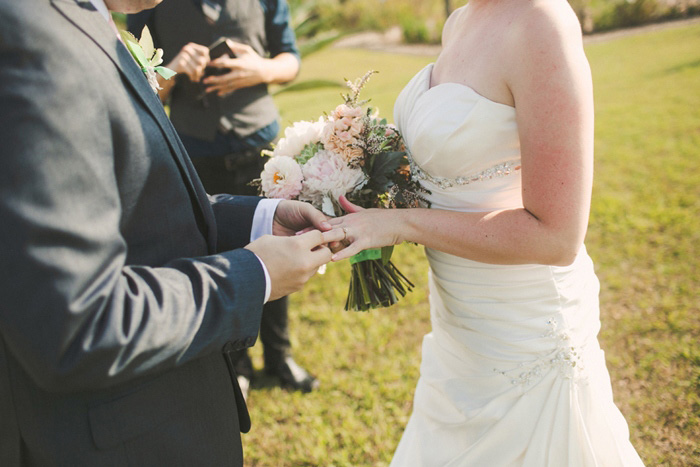 groom putting ring on bride's finger