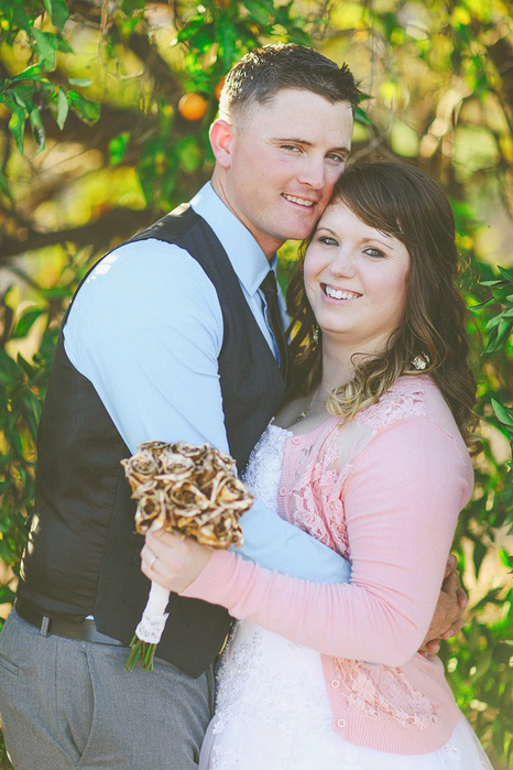 bride in pink cardigan with gold rose bouquet