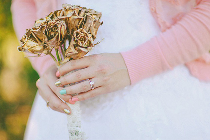 bride with pastel nails and gold rose bouquet