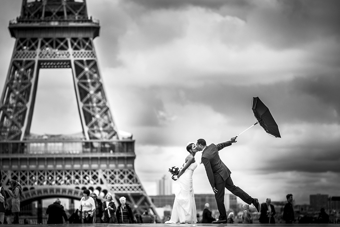 bride and groom with umbrella in front of eiffel tower 