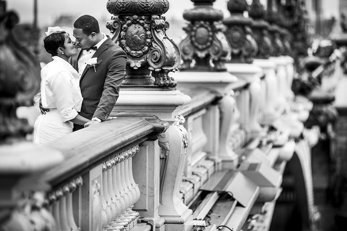 bride and groom kissing on bridge in Paris