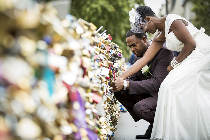 bride and groom placing lock Paris bridge