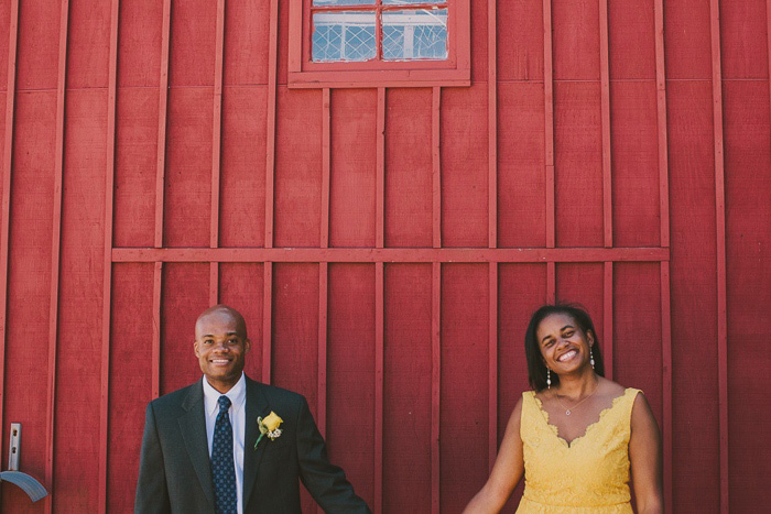 bride and groom in front of red building