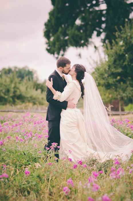 bride and groom kissing in field of flowers