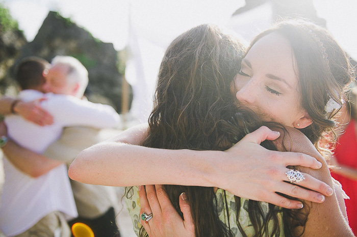 bride and groom hugging guests on the beach