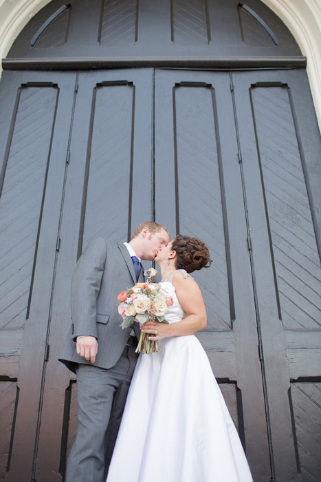 bride and groom kissing in front of church