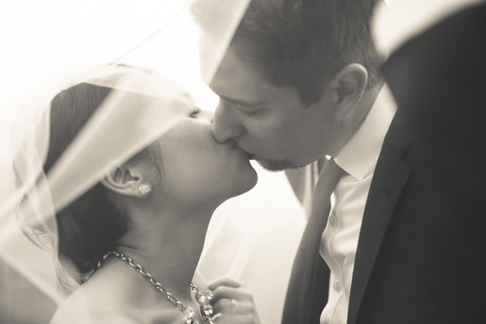 Bride and groom kissing under veil
