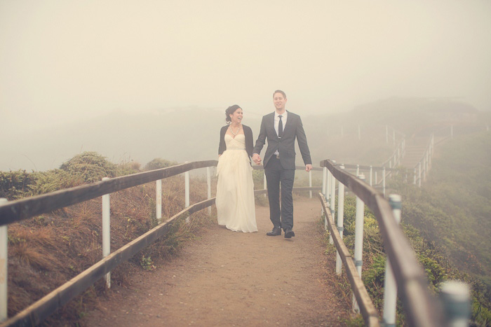 bride and groom walking through the fog