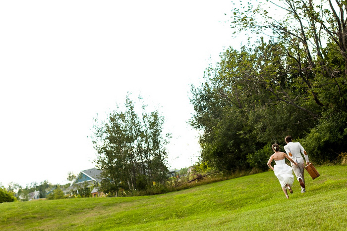 bride and groom running with suitcase