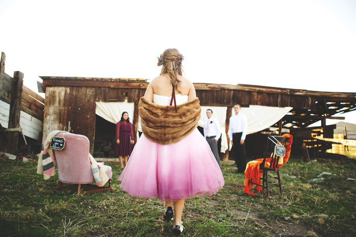 Bride in pink dress and fur stole walking down the aisle