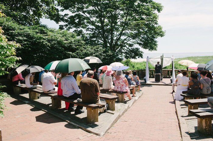 wedding guests with umbrellas at outdoor wedding ceremony