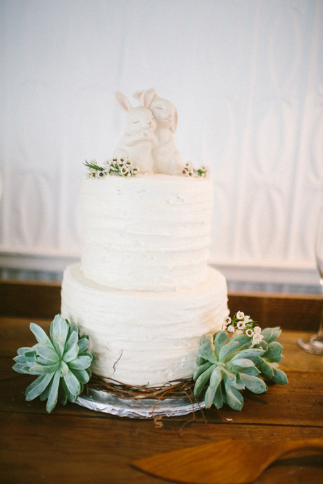 white wedding cake with succulents and rabbit cake topper