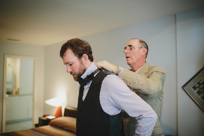groom putting on his bow tie