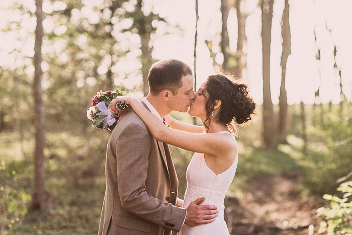 bride and groom kissing in the woods