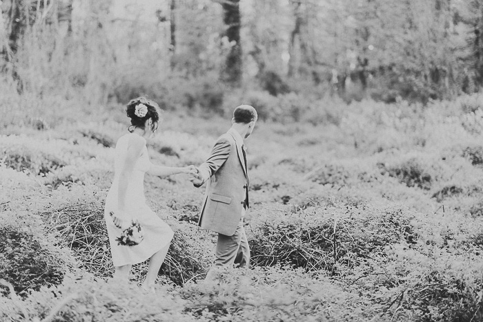 bride and groom walking through overgrown field