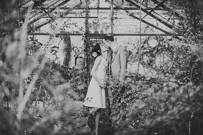 bride and groom kissing in abandoned greenhouse