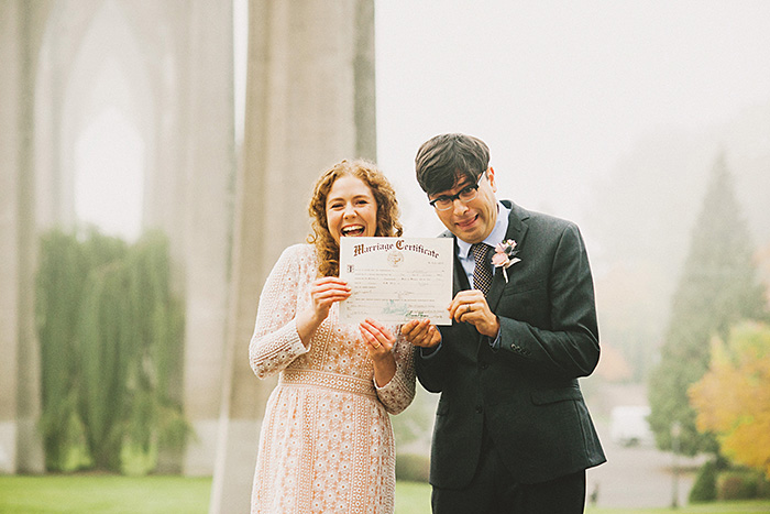 bride and groom holding up marriage certificate