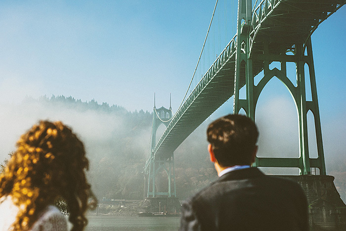 bride and groom looking up at bridge