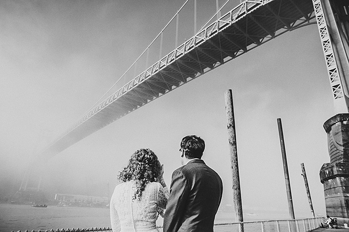 bride and groom looking up at bridge