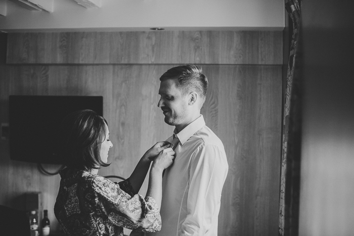 bride helping groom with his tie