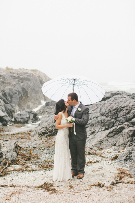 bride and groom on the beach in the rain