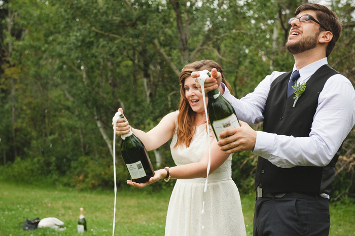 bride and groom popping champagne bottles