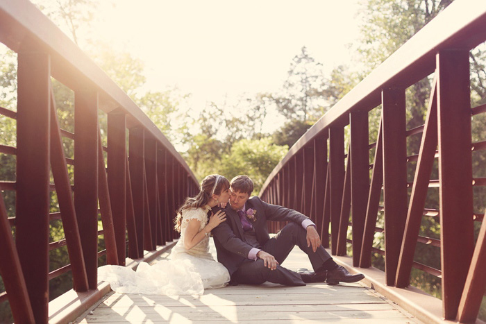 bride and groom sitting on wooden bridge