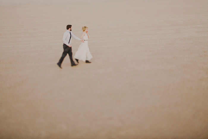 bride and groom walking through the desert