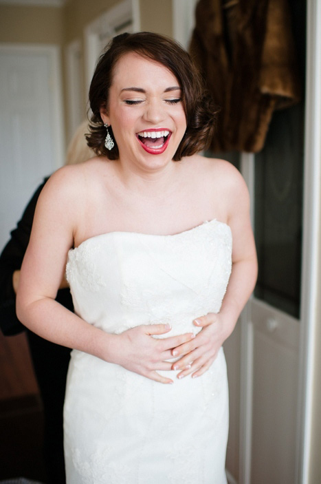 bride laughing while getting dressed