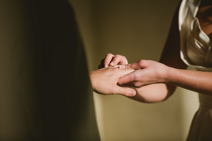 bride putting ring on groom's finger