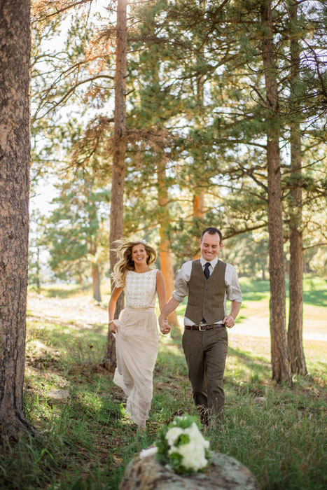 bride and groom running through the woods