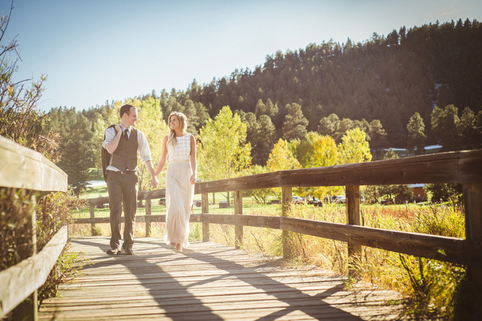 bride and groom walking across wooden bridge