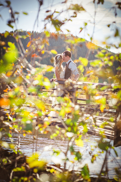 bride and groom kissing on bridge