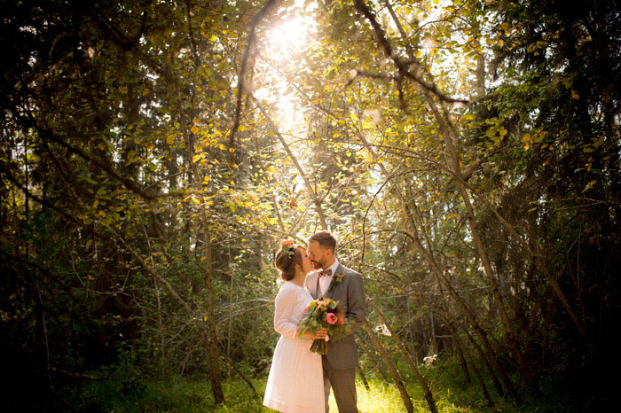 bride and groom kissing in the woods