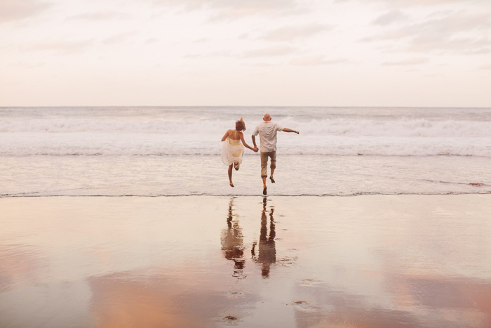 bride and groom skipping along beach in Hawaii