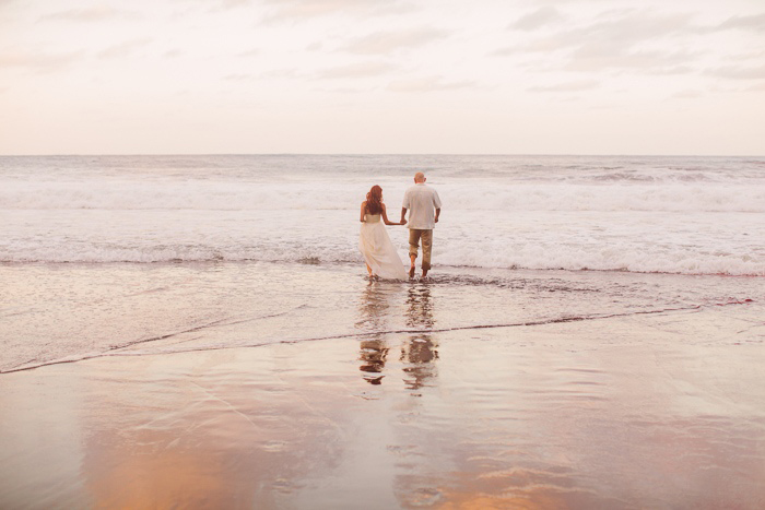 bride and groom walking into the ocean