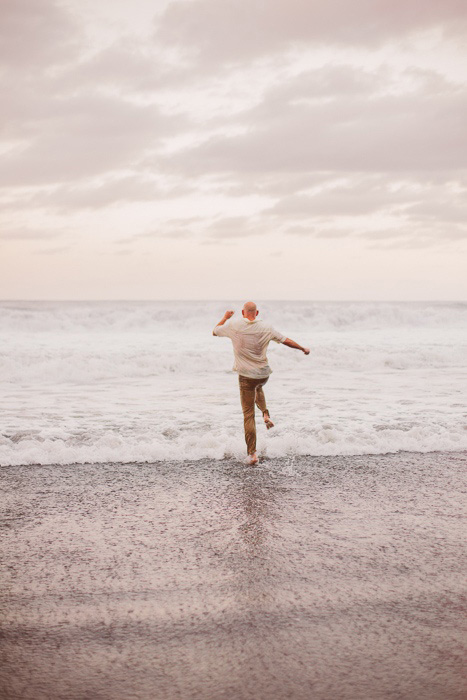 groom skipping in the surf