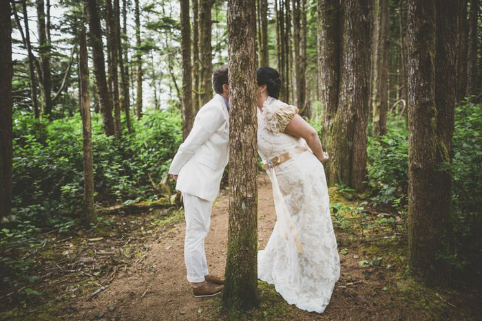 brides kissing behind tree