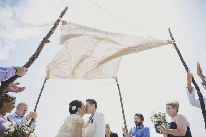 brides kissing under wedding canopy