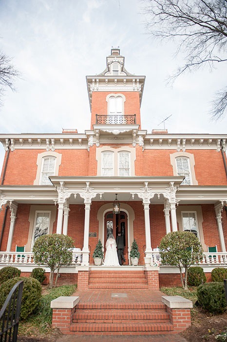 bride and groom in front of historic house