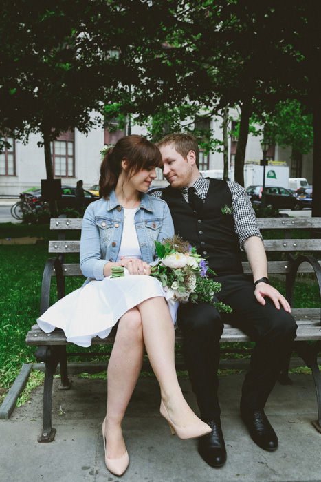 bride and groom sitting on park bench